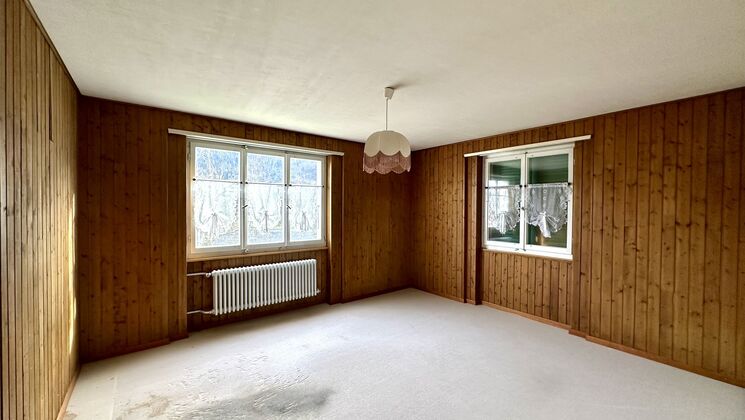 une pièce vide avec des murs en bois et une grande fenêtre dans une maison