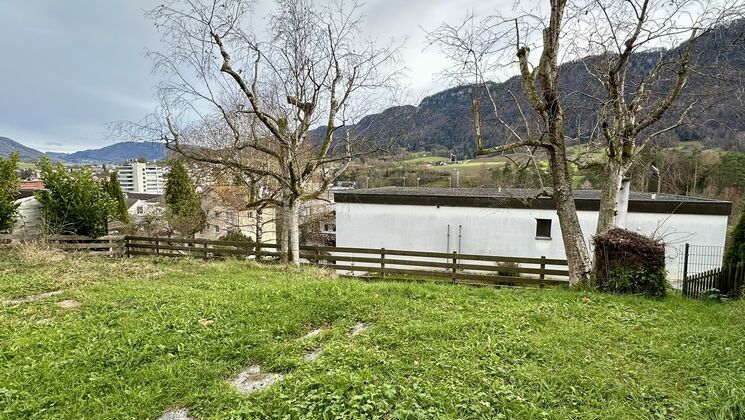 une maison blanche sur une colline avec des arbres et des montagnes en arrière-plan