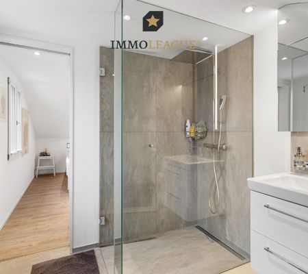 Das Bad überzeugt mit bodentiefer Dusche, klarem Design und einem praktischen Stauraum. 