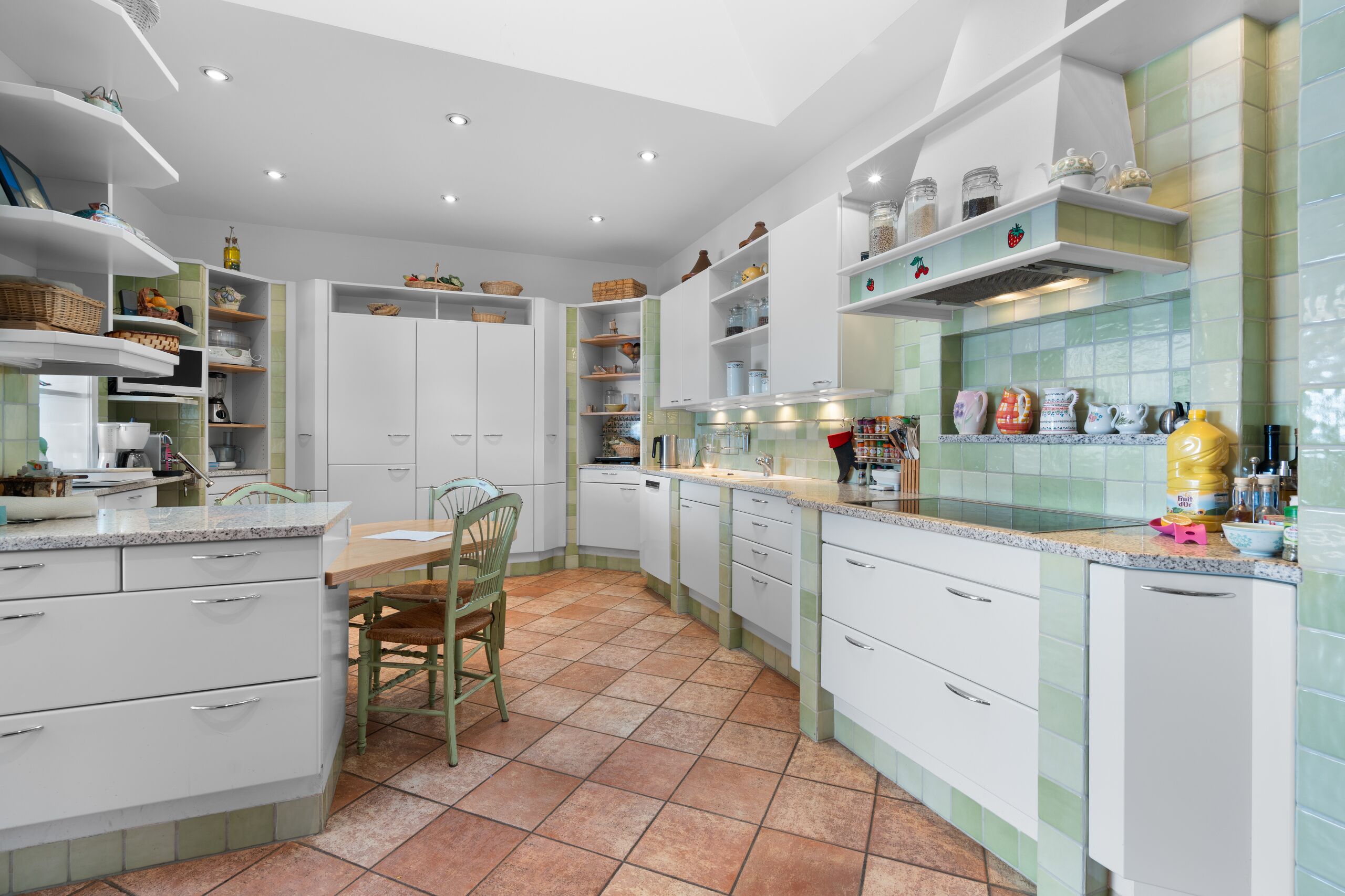 a large kitchen with white cabinets and green chairs