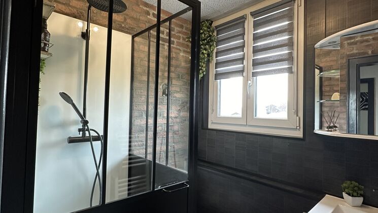 une salle de bains avec des murs noirs, une baignoire blanche, des toilettes, un lavabo et un miroir