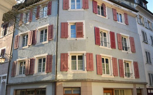 Maison typique de Porrentruy donnant sur une rue pavée tranquille.