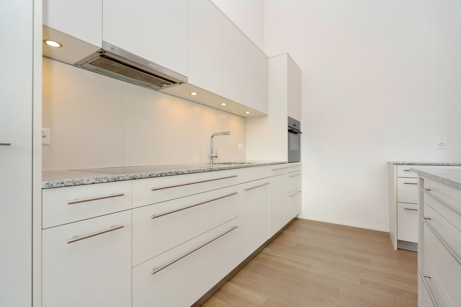 Offene, moderne Küche mit Glaskermaikherd, Backofen, Geschirrspüler, Kühlschrank mit Gefrierfach und genügend Stauraum