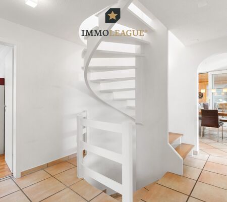 Die geschwungene Wendeltreppe verbindet die Geschosse mit eleganter Linienführung und nimmt die runde Form des Durchgangs zum Essbereich auf.