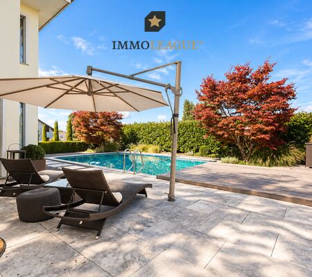 der Garten eines modernen Hauses mit einem großen Swimmingpool und einer Terrasse mit Stühlen und einem Sonnenschirm
