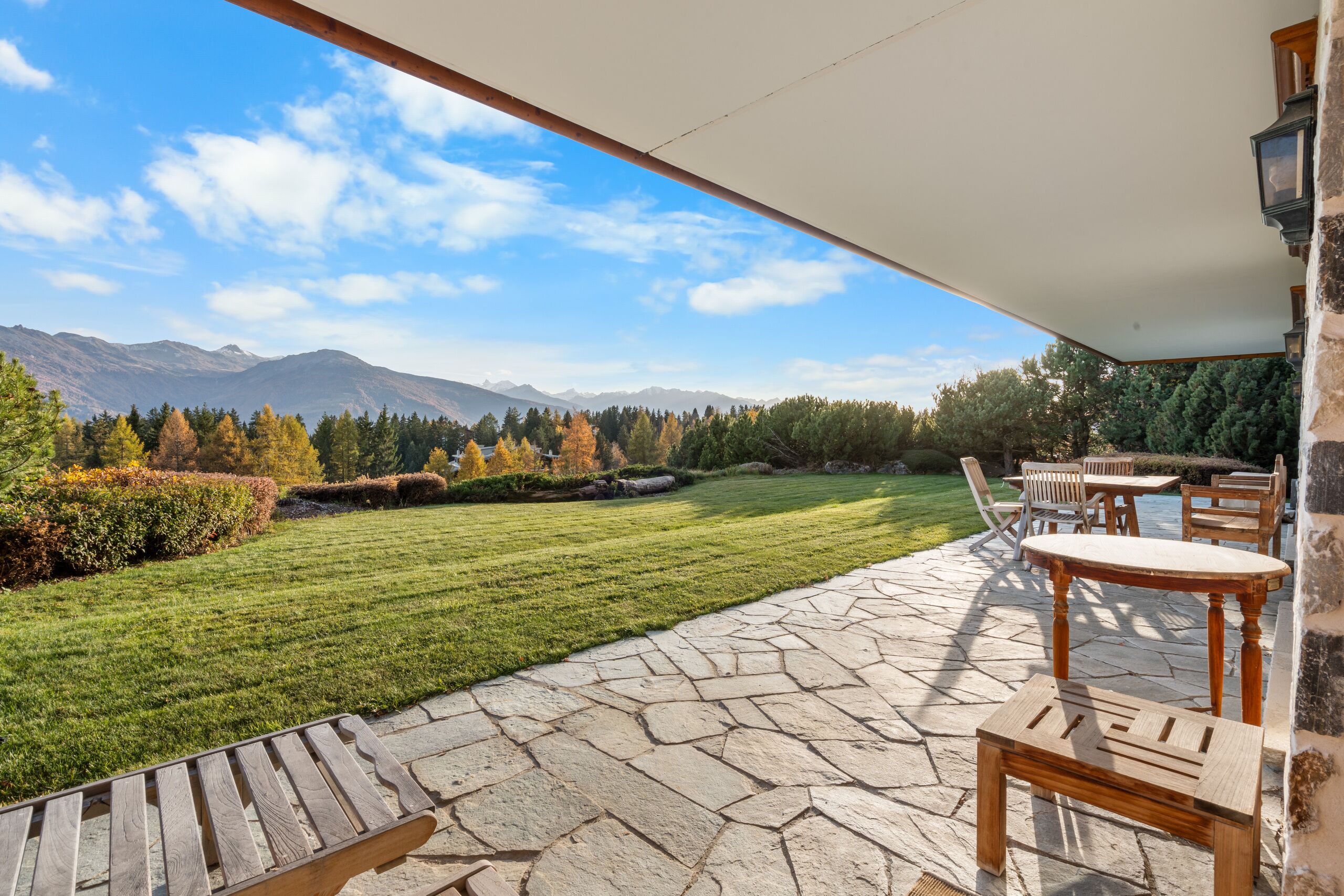 a patio with chairs overlooks a large lawn
