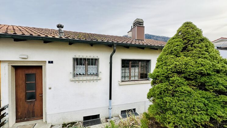 un vieux bâtiment devant lequel se trouve un petit arbre