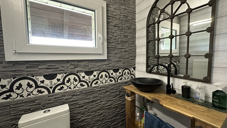 une salle de bains avec des toilettes, un lavabo et un miroir blancs et des carreaux noirs et blancs