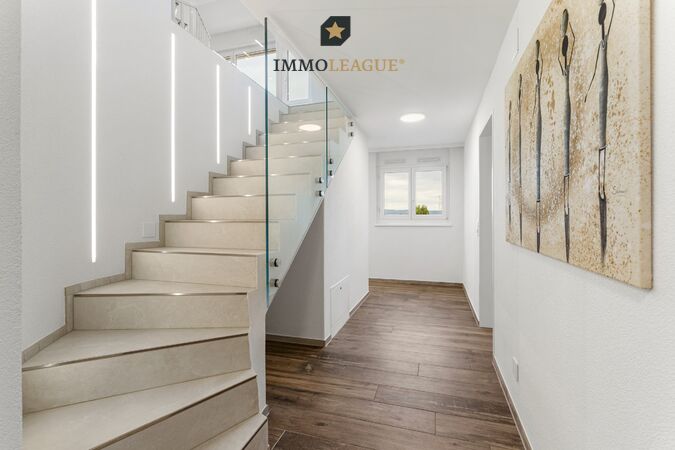 Beleuchtung als Gestaltungselement: Feine LED-Lichtlinien führen die Treppe hinauf. Integrierte Einbauschränke bieten Stauraum, wo man ihn braucht.