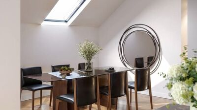 a modern dining area with a black table and chairs and a skylight on the wall above the dining table