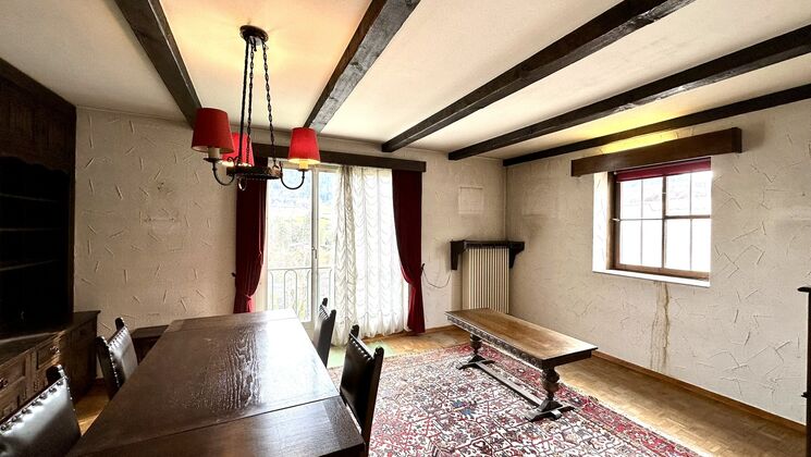 une pièce avec un plafond voûté, une grande fenêtre et une table en bois avec un banc