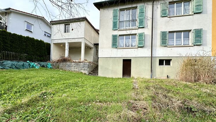 une maison avec une grande pelouse et de l'herbe devant le bâtiment