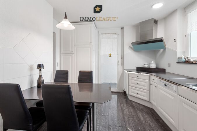 Charmante, helle Küche im Landhausstil mit Vollflächeninduktionskochfeld, Steamer und Backofen. Das angrenzende Reduit bietet wertvollen Stauraum.