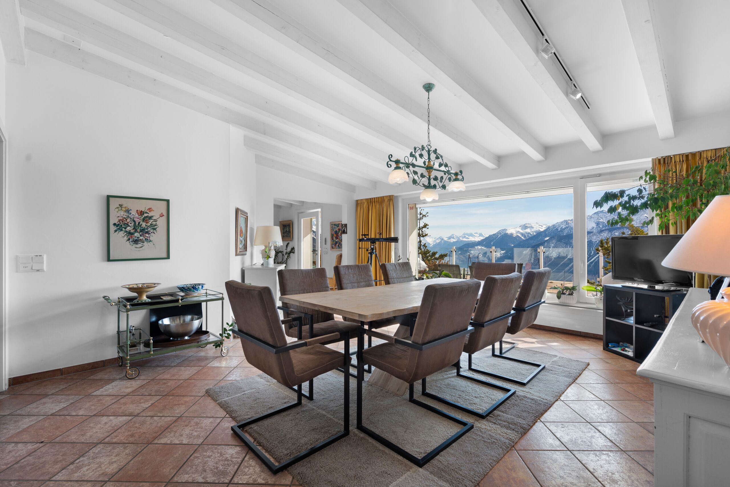 a large room with a dining table and chairs, with a view of the mountains from the kitchen and living room