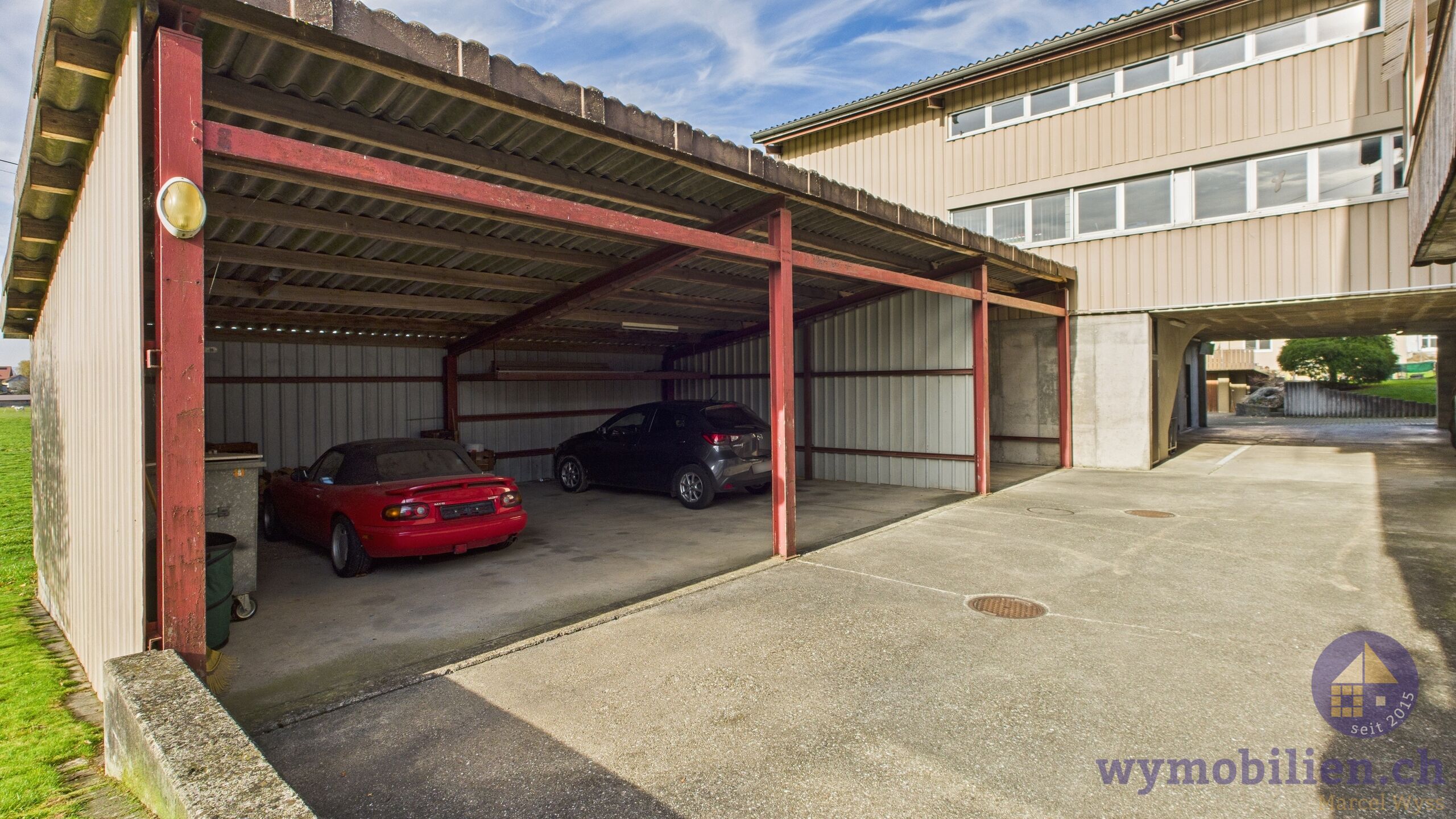 Blick vom Vorplatz auf die gedeckten Autounterstände 