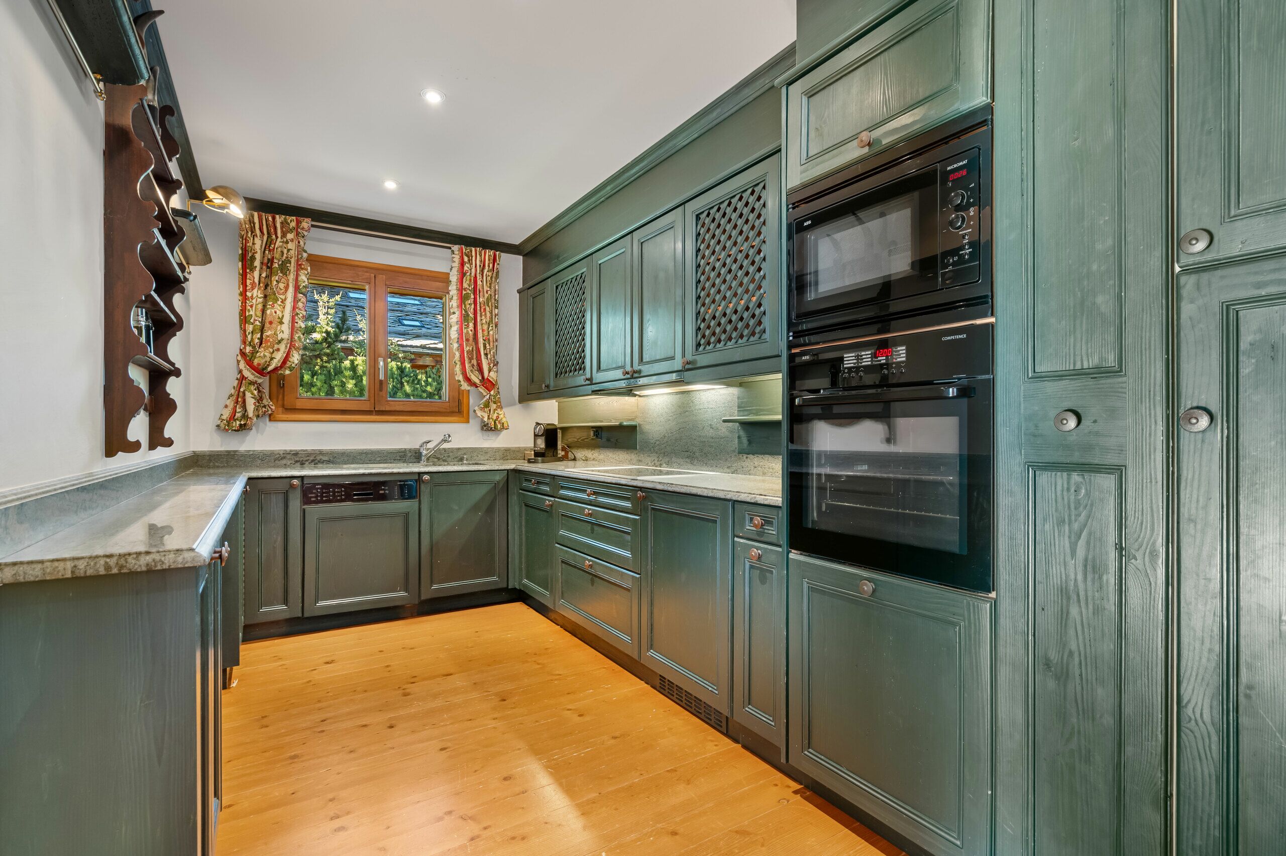 a large kitchen with green cabinets and stainless steel appliances