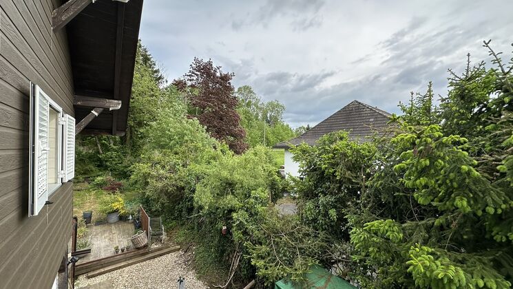 la cour arrière d'une maison avec une terrasse et des arbres dans la cour