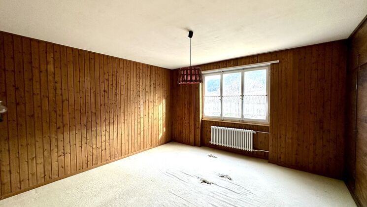une pièce vide dans une maison avec des murs en bois et une grande fenêtre au sol