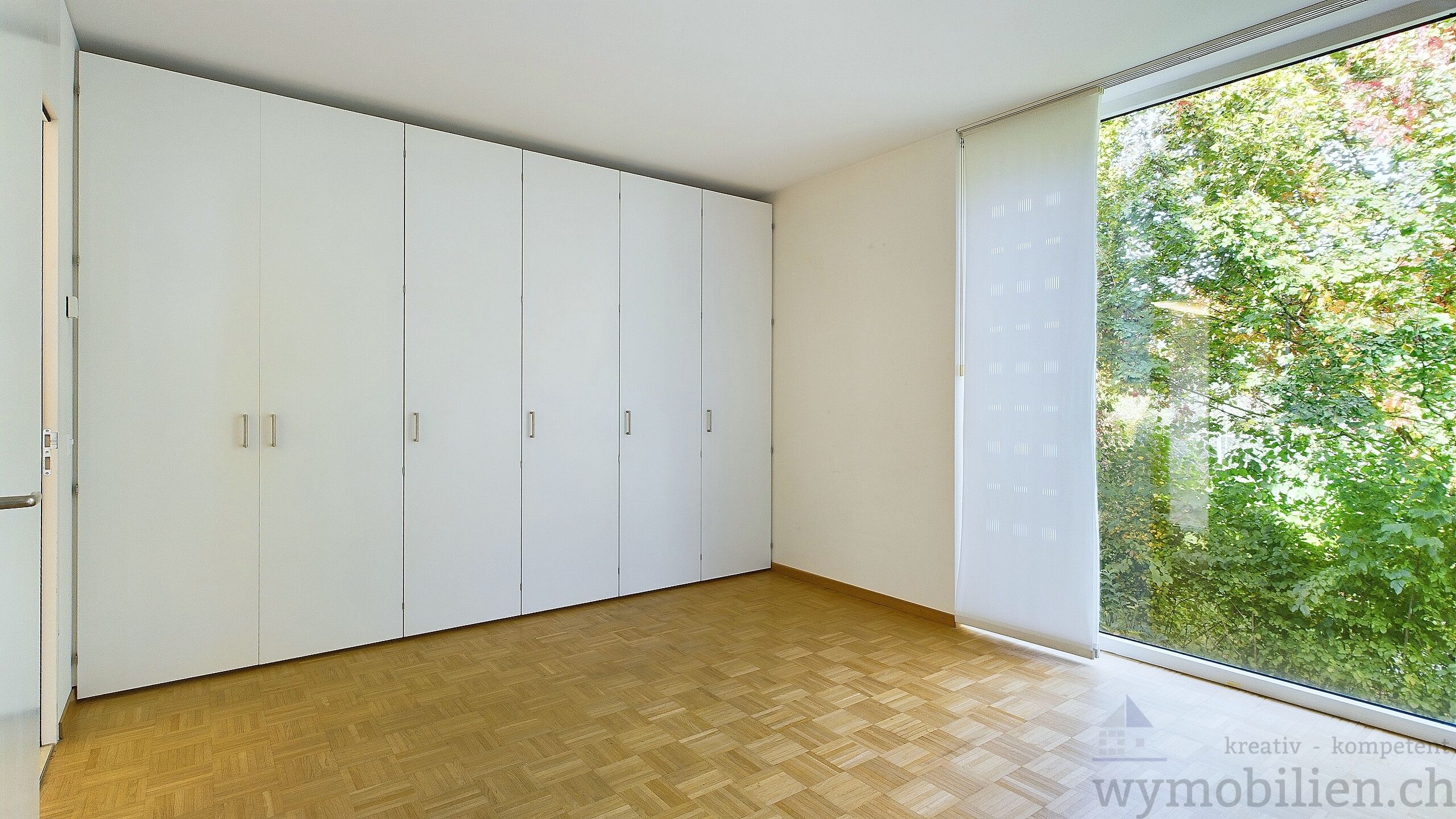 Zimmer mit Einbauschränken und Blick ins Grüne 