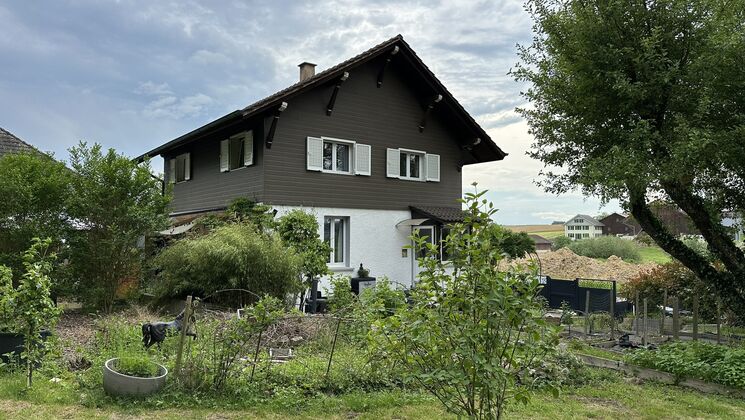 une maison avec un jardin et des arbres devant elle