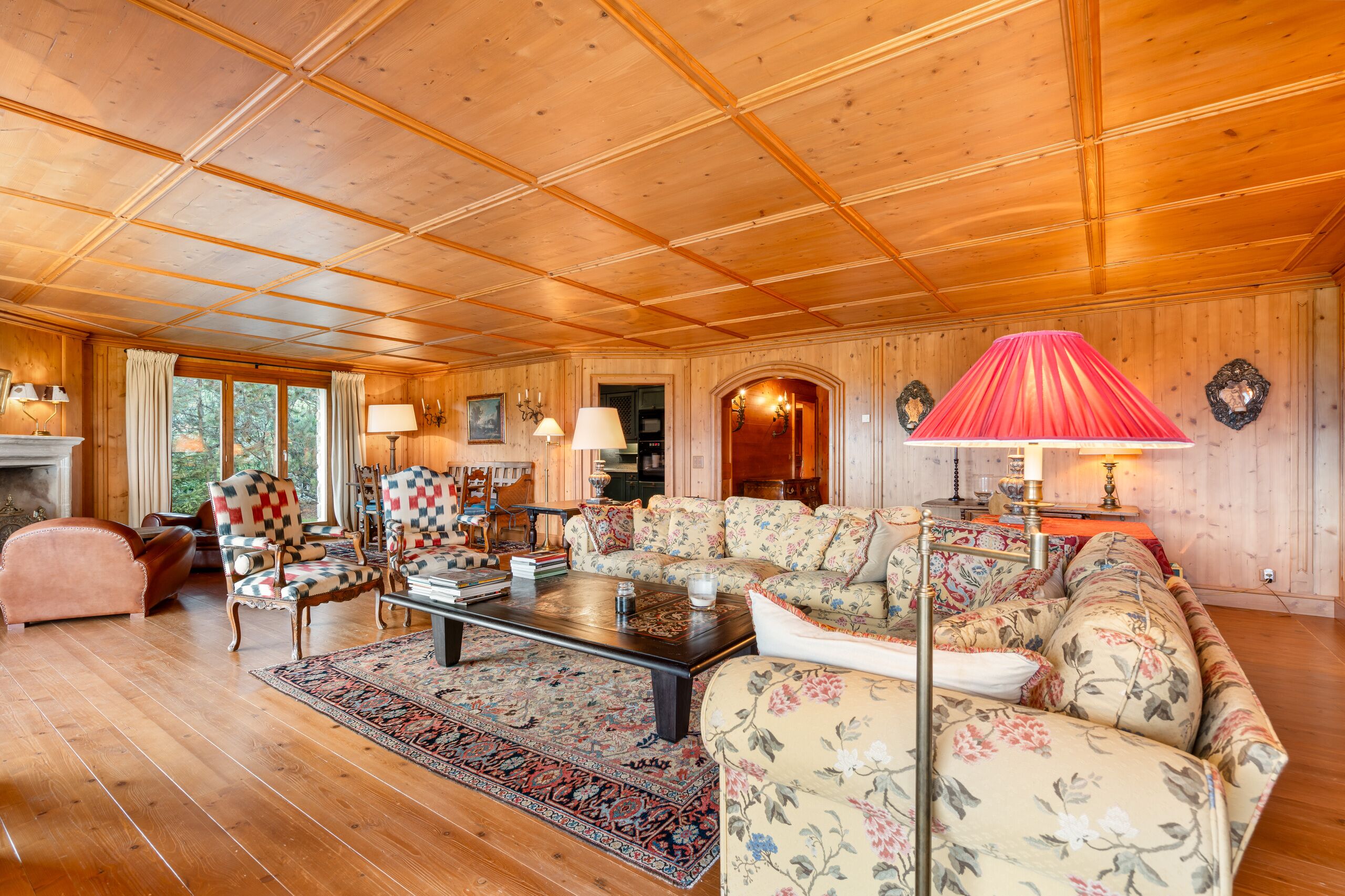 a large room with a wooden ceiling, a couch, a lamp and a fireplace