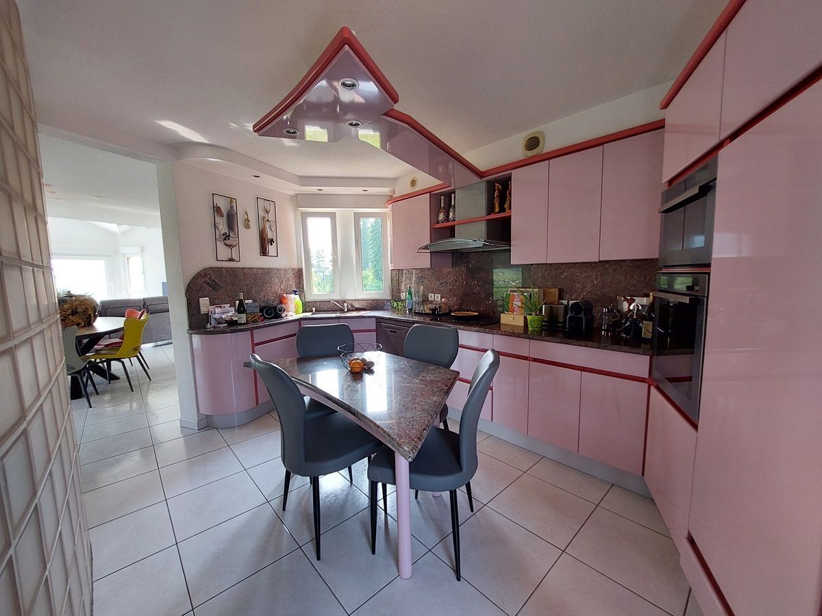 Cuisine équipée avec des armoires roses et une table centrale.