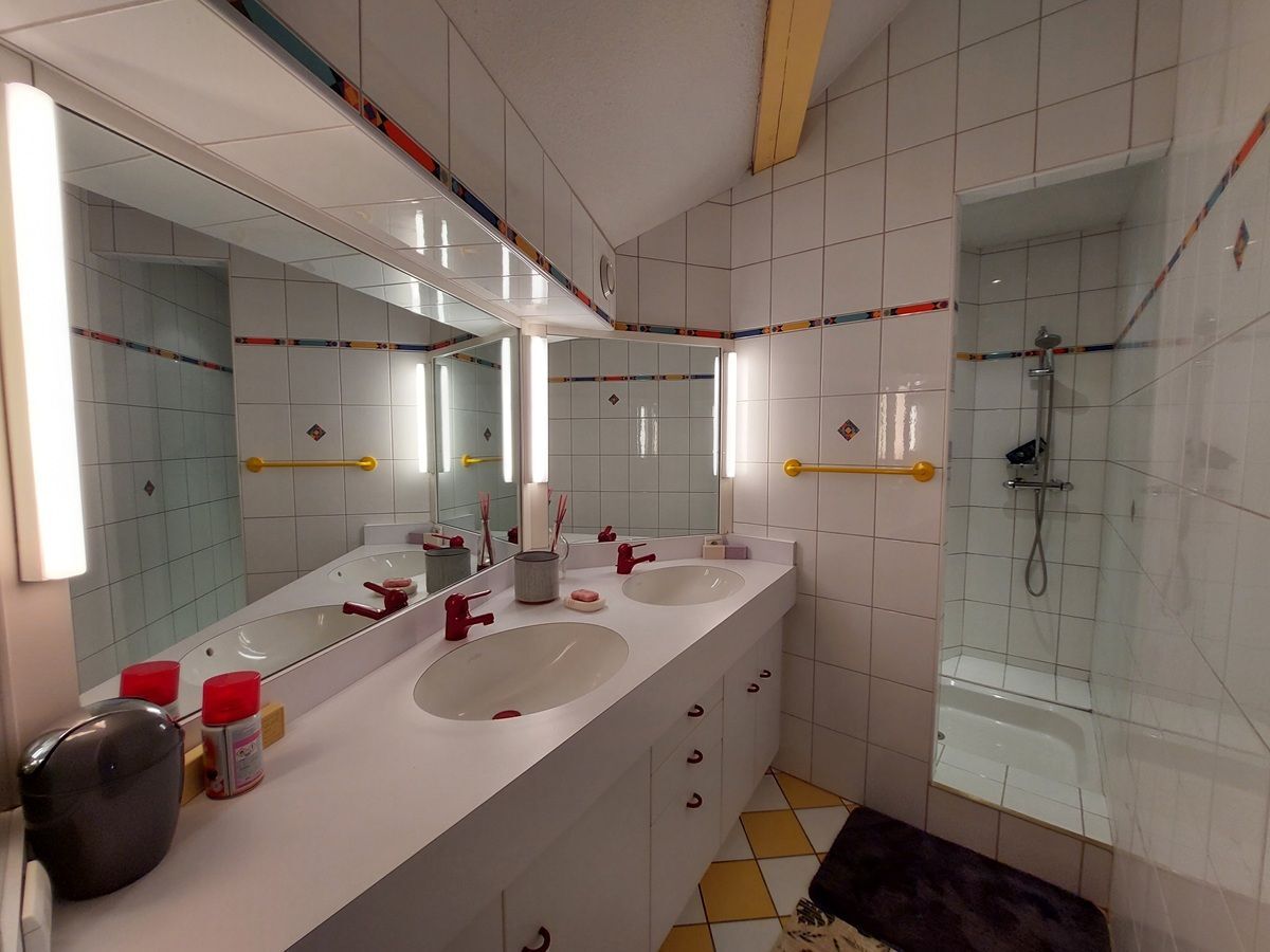 Double vasque et douche carrelée avec miroir éclairé.