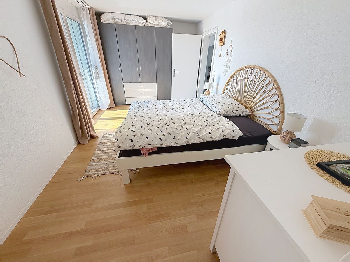 Chambre lumineuse avec parquet et grande armoire.