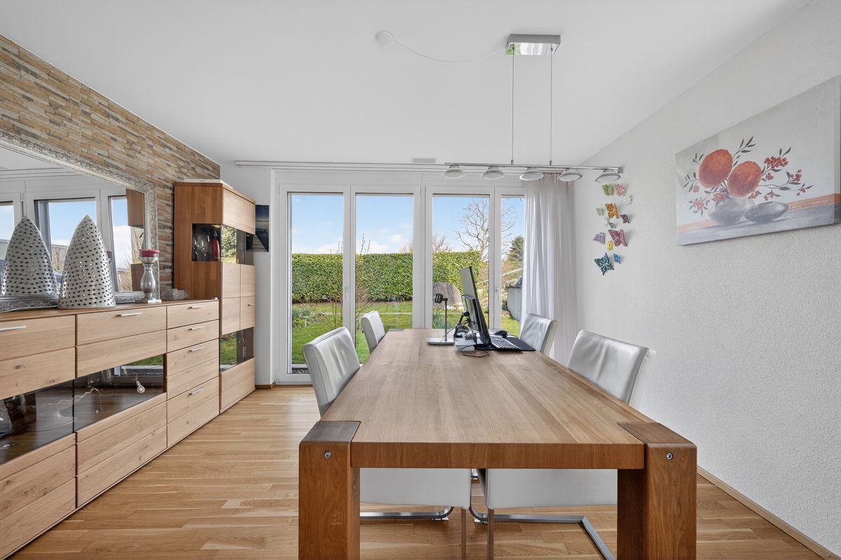 Grosszügiger Essbereich mit Blick auf den Garten durch grosse Fenster.
