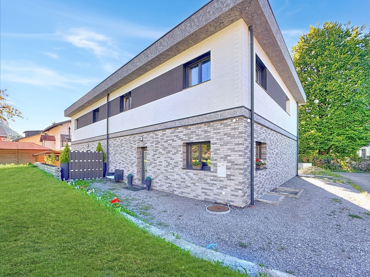 Vue extérieure d'une maison avec jardin et terrasse.
