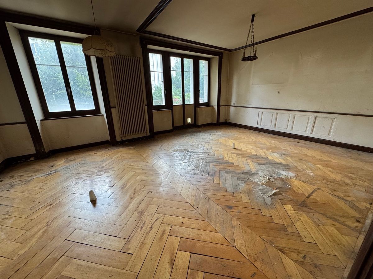 Salon avec parquet en bois et grandes fenêtres.