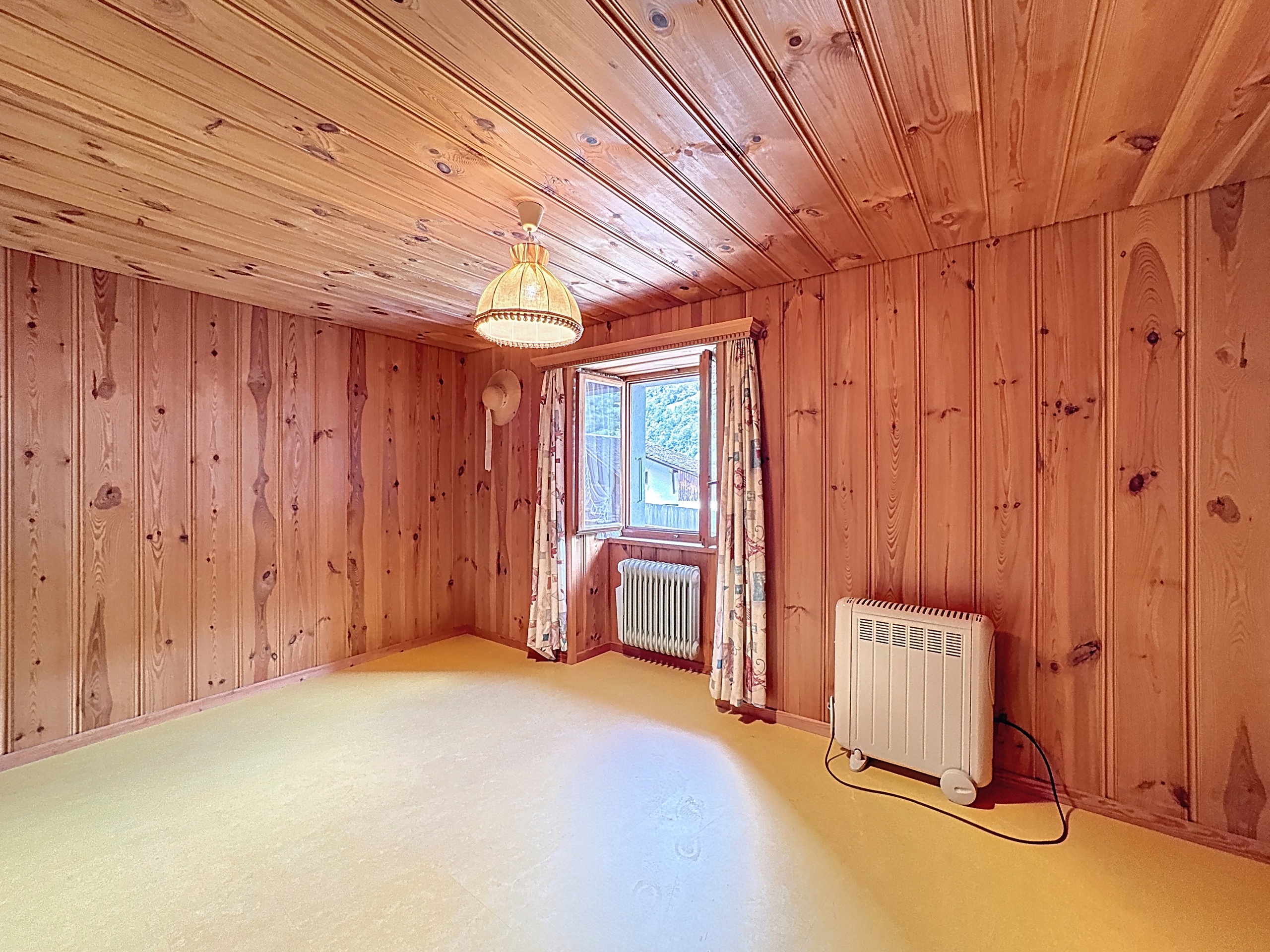 une pièce vide avec des murs et un plafond en bois et une grande fenêtre