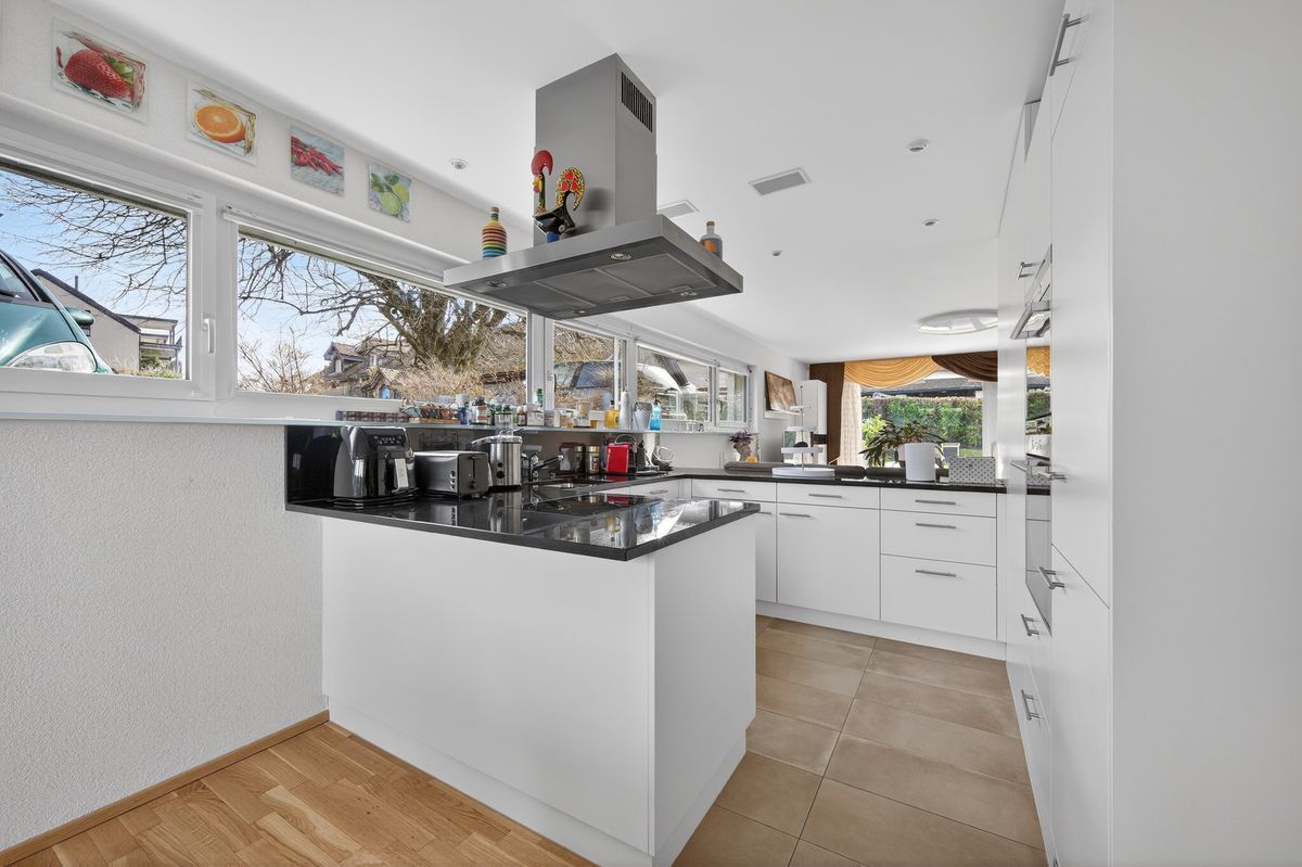 Moderne Küche mit grossen Fenstern und viel Arbeitsfläche.