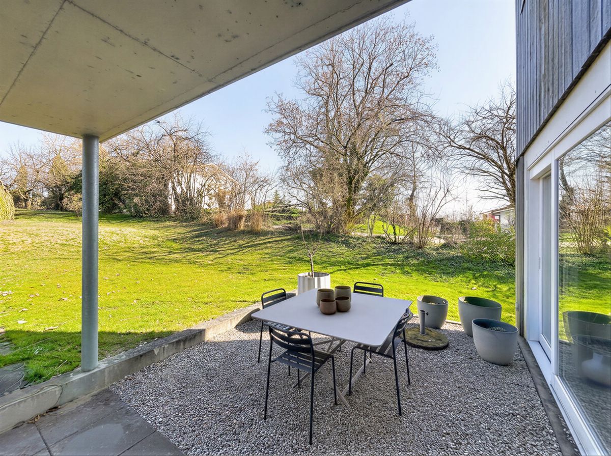 Terrasse donnant sur un jardin arboré, idéale pour les repas en plein air.