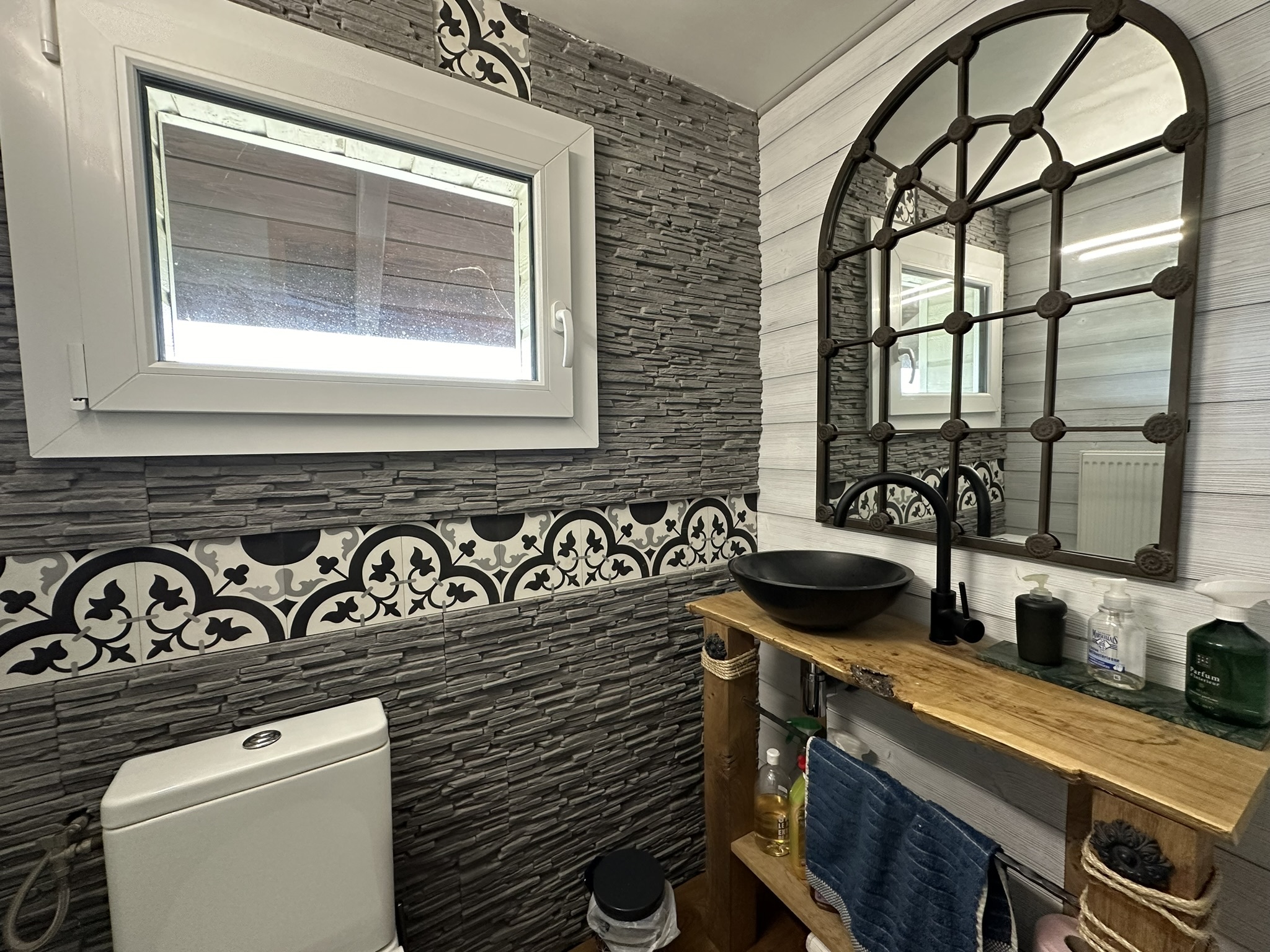 une salle de bains avec des toilettes, un lavabo et un miroir blancs et des carreaux noirs et blancs