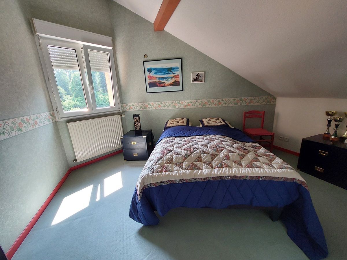 Chambre mansardée avec lit double et vue sur jardin.