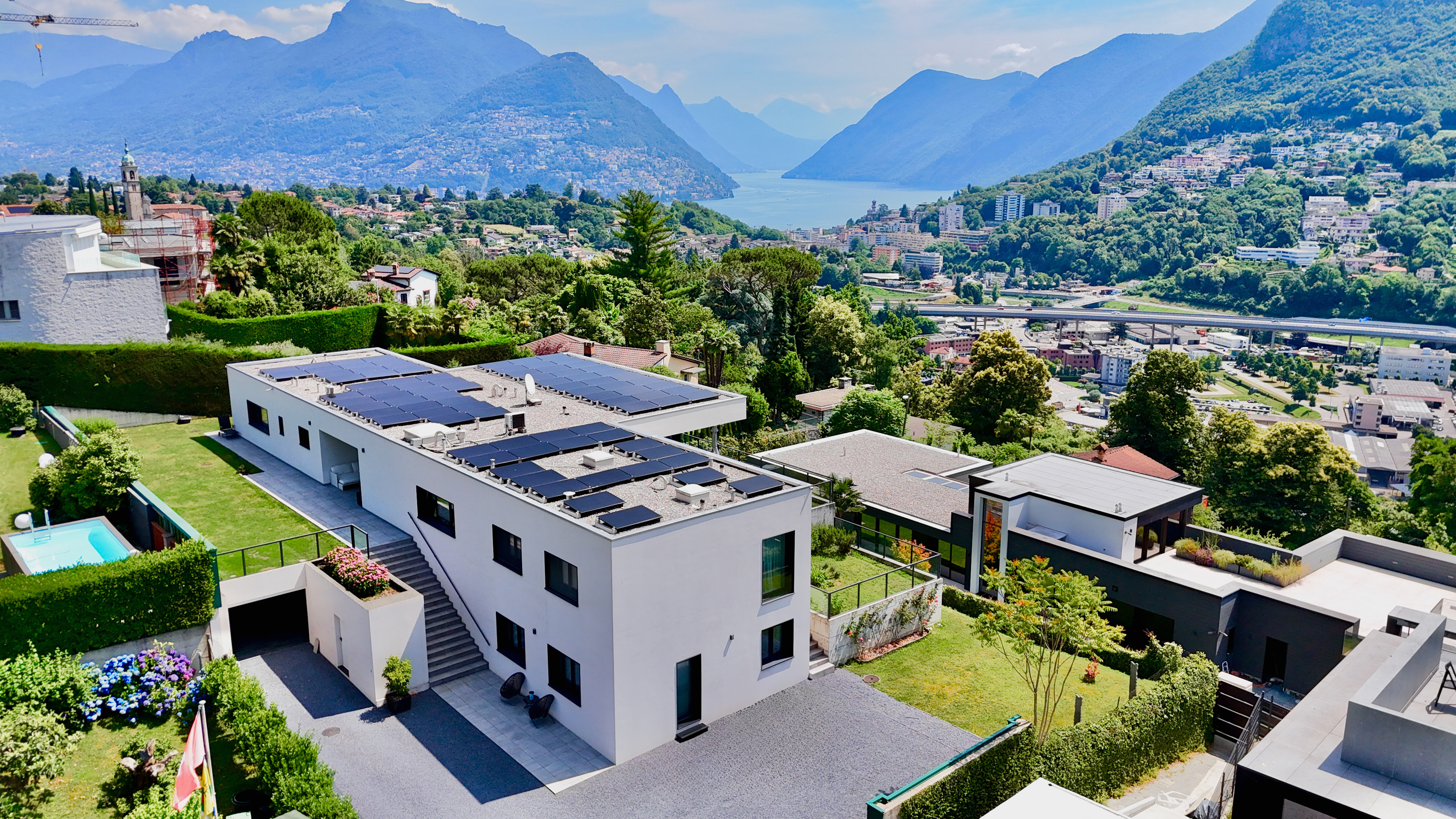Ultra moderna villa di lusso con splendida vista sul lago e sul verde A Montagnola (Collina d'Oro), in una prestigiosa zona residenziale molto tranquilla e soleggiata, a 4 km dal centro di Lugano e a soli 450 metri dalla scuola americana TASIS, proponiamo in vendita questa ultra moderna villa di lusso con splendida vista panoramica sul Lago di Lugano e sulle montagne circostanti.
Costruita nel 2018 con i materiale e finiture di pregio, la villa dispone di 6 camere da letti, 8 bagni, una grande terrazza coperta (lounge estivo) con giardino pianeggiante, zona SPA con piscina interna riscaldata, sala fitness, sauna, hammam, vasca idramassaggio e un ampio garage per 4 auto.
La villa con una superficie totale di ca. 680 mq e’ disposta su 2 livelli come segue:
PIANO SUPERIORE:
Grazioso atrio d’ingresso, soggiorno con le grandi finestre a tutta altezza e con magnifica vista panoramica sulle montagne circostanti, sala da pranzo, uscita sulla terrazza coperta (lounge estivo) e giardino pianeggiante; cucina con sala da pranzo, WC ospiti, 2 camere da letto singole con i bagni en-suite, sala hobby, camera da letto padronale con cabina armadio, bagno en-suite e uscita sul giardino, studio/camera da letto, bagno, 2 cabine armadio
PIANO TERRA:
Bilocale con entrata indipendente (soggiorno con cucina, camera con bagno en suite); camera di servizio/ospiti, bagno, locale rack, lavanderia, home cinema, zona wellness con piscina riscaldata, vasca idromassaggio, sauna, hammam, sala fitness, doccia, bagno, spogliatoio, locale tecnico, autorimessa di 100 mq per 4 auto, 2 parcheggi esterni
La villa utilizza fonti energetiche alternative ed é dotata di un impianto domotico di ultima generazione, aria condizionata e sistema di allarme.
Il riscaldamento usa la geotermia, come aiuto (circa 12 gradi) alla termopompa classica elettrica. Vi sono 5 sonde geotermiche che vanno a una profondità di 140 metri e che consentono un ricircolo di acqua più calda nelle serpentine a pavimento.
Vi è un serbatoio interrato di 10'000 litri per l'irrigazione del prato, completamente gestita dalla domotica, quindi anche da remoto.
Vi è una termopompa per il raffrescamento, che d'estate contribuisce ad abbassare la temperatura interna della casa di 5/6 gradi, senza bisogno di utilizzare l'aria condizionata.