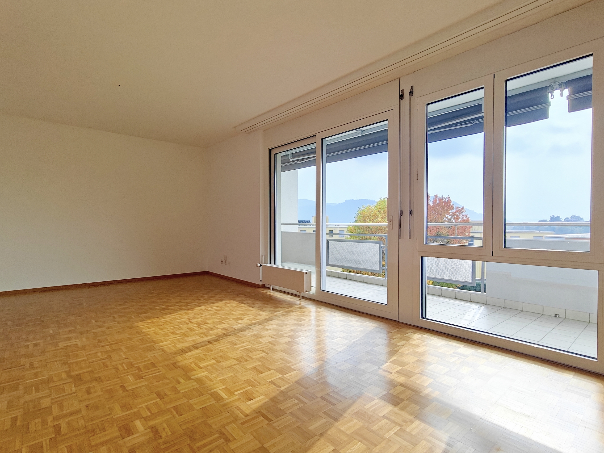 an empty room with wooden floors, large windows and sliding doors an empty room with wooden floors, large windows and sliding doors