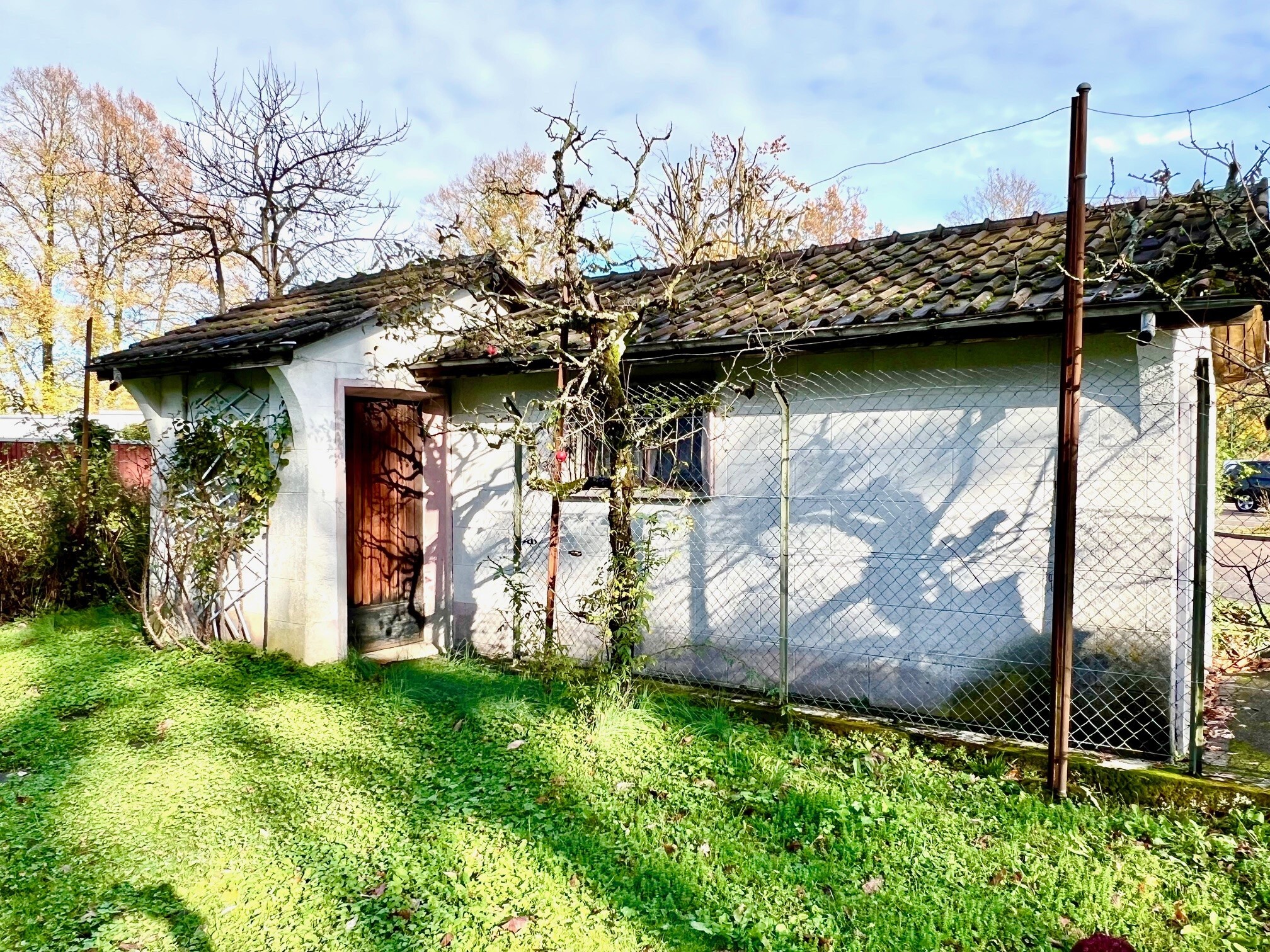 an old house with a small door behind a fence