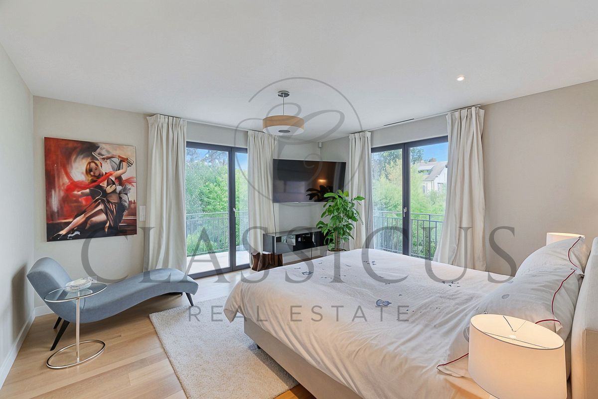 Chambre avec TV murale et grandes fenêtres donnant sur le jardin.