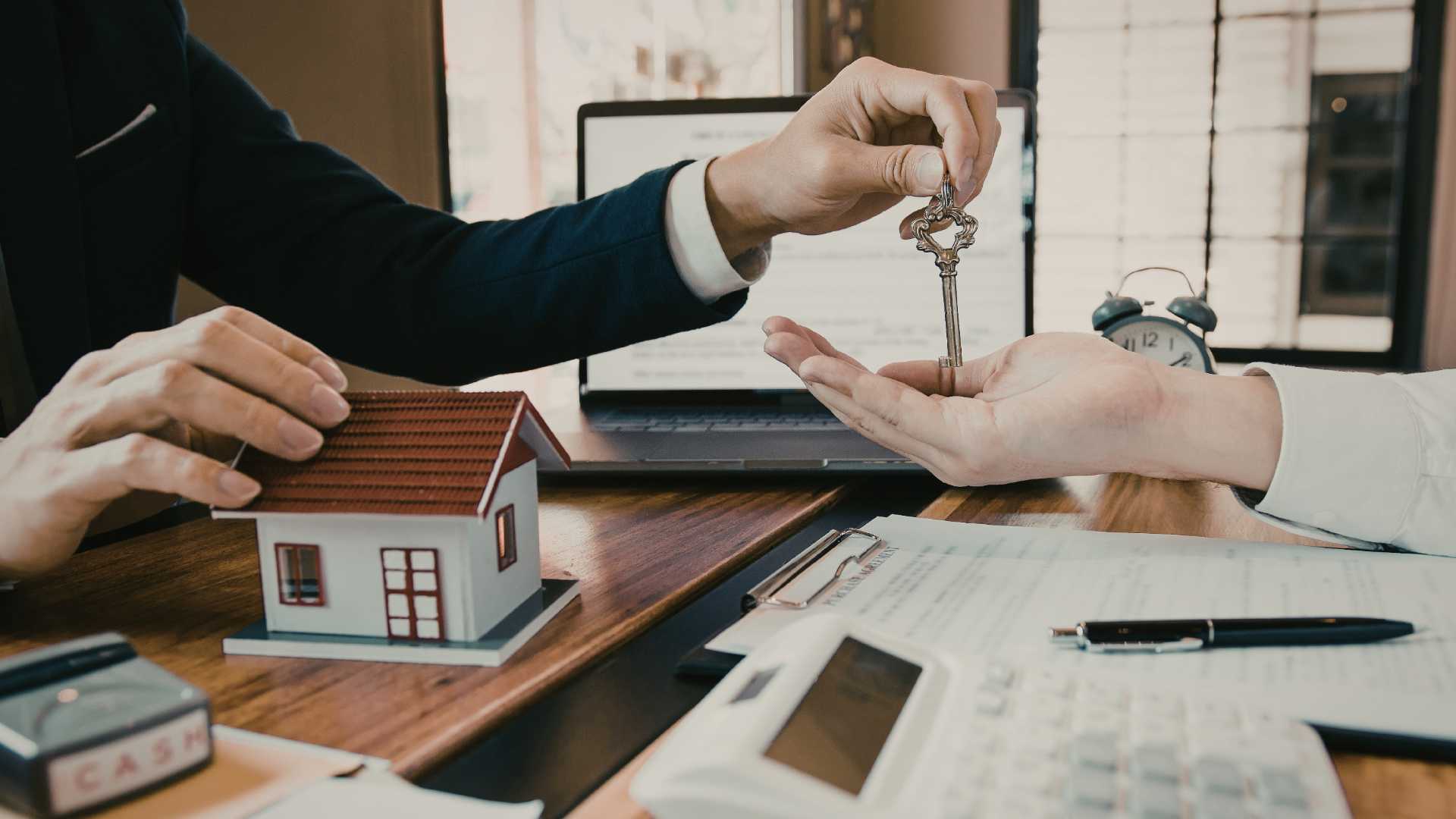 Une personne remet les clés d’un bureau à une autre personne, symbolisant la transmission de propriété.