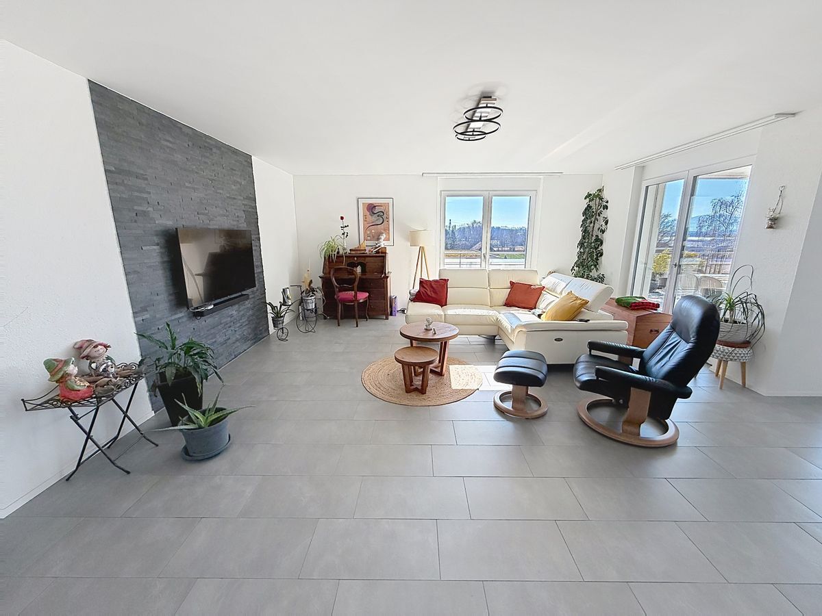 Espace de vie lumineux avec canapé d'angle et accès terrasse.