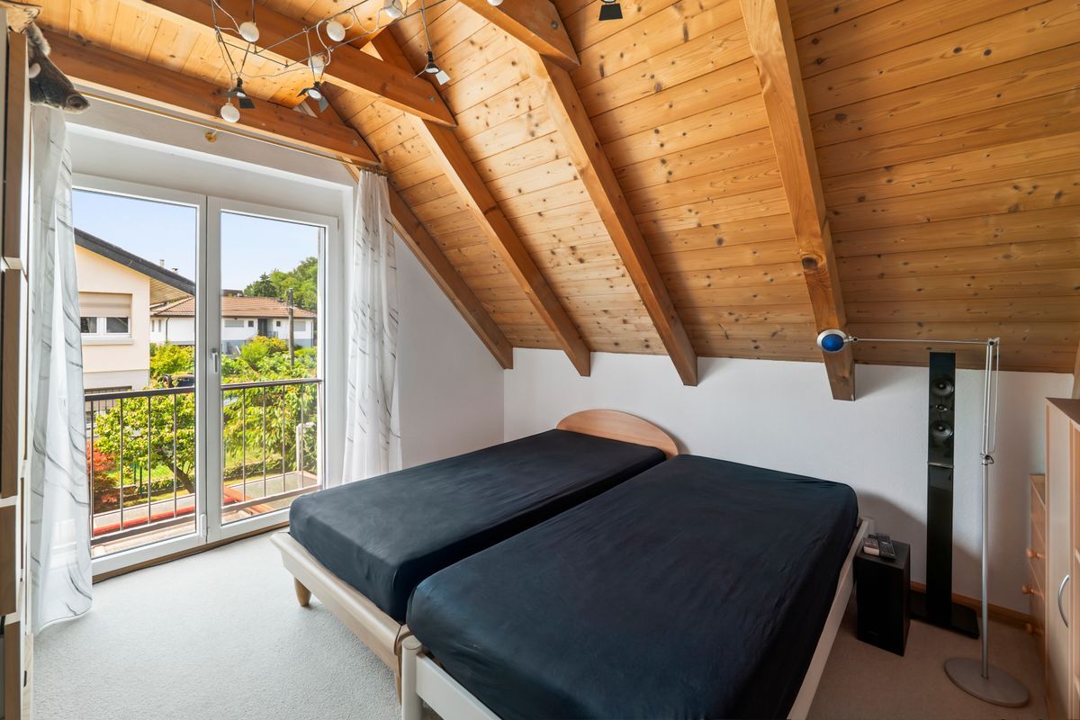 Dachgeschoss-Schlafzimmer mit Holzbalkendecke und Balkon. Dachgeschoss-Schlafzimmer mit Holzbalkendecke und Balkon.