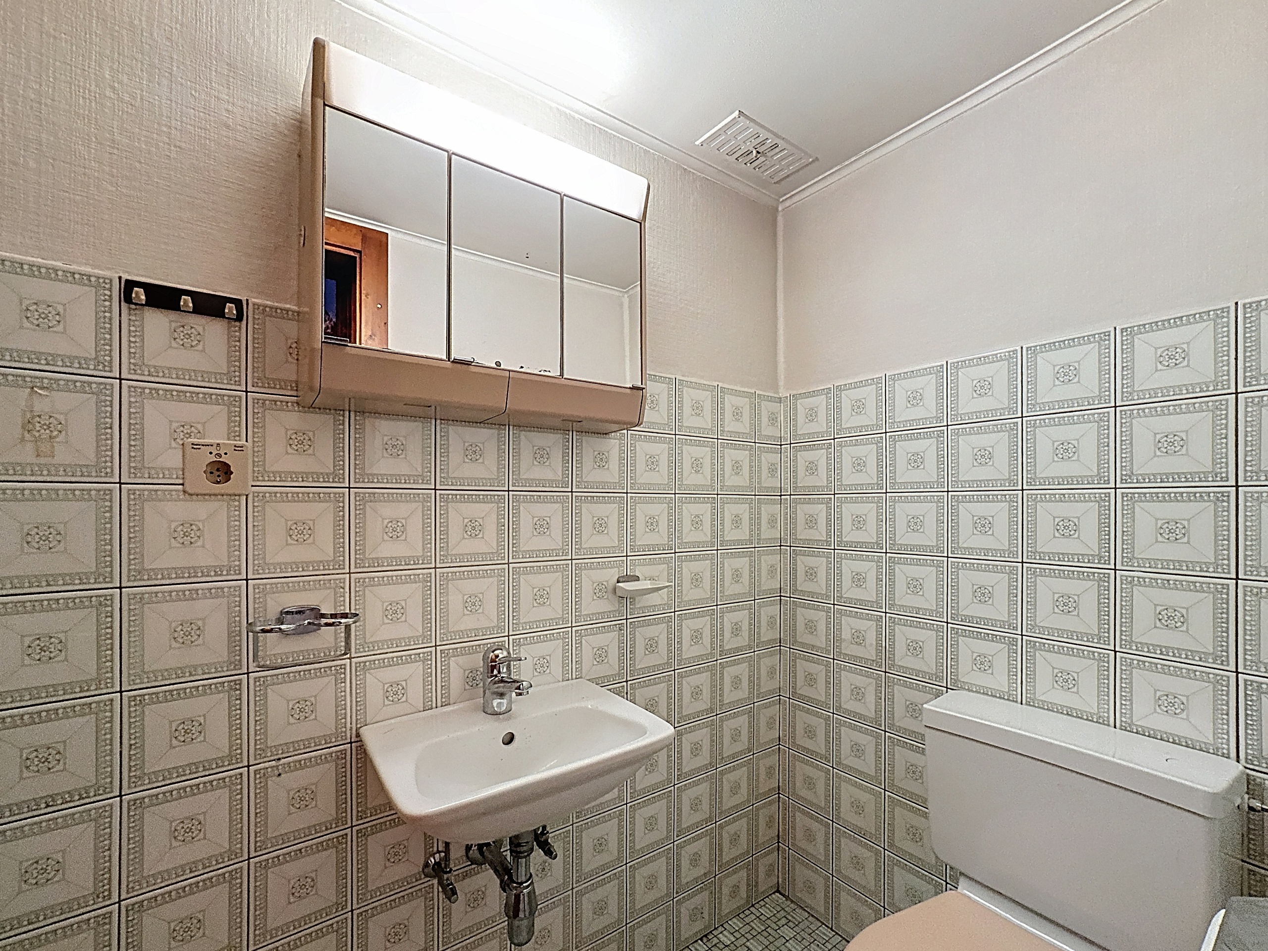 une petite salle de bain avec toilettes, lavabo et miroir