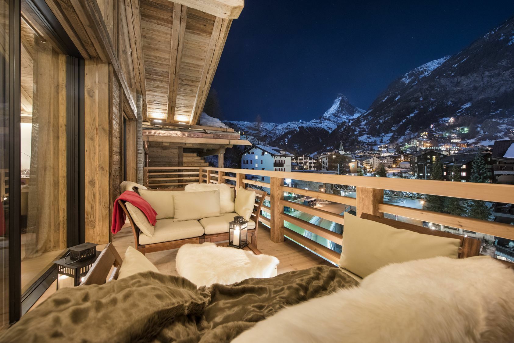 ein großes Zimmer mit einem Balkon mit Blick auf die nächtlichen Berge ein großes Zimmer mit einem Balkon mit Blick auf die nächtlichen Berge