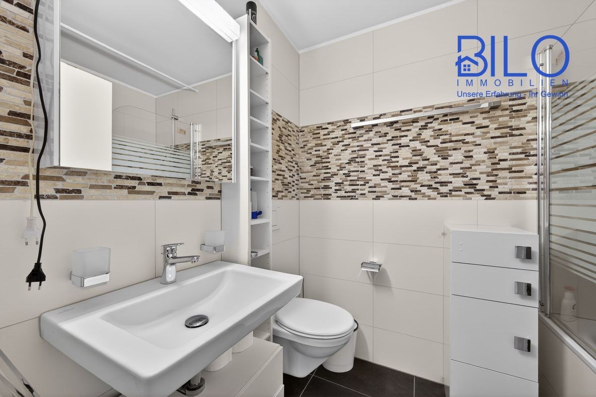 Modernes Badezimmer mit gemusterten Fliesen und Duschbadewanne. Modernes Badezimmer mit gemusterten Fliesen und Duschbadewanne.