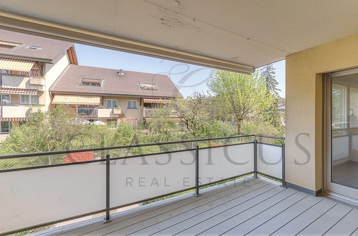 Balcon avec vue sur jardin et bâtiments voisins.