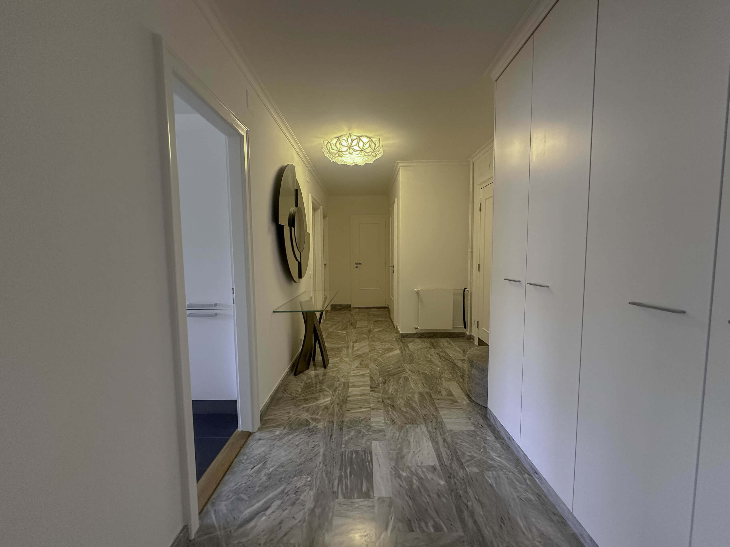 un long couloir aux murs blancs avec une porte menant à une autre pièce vide