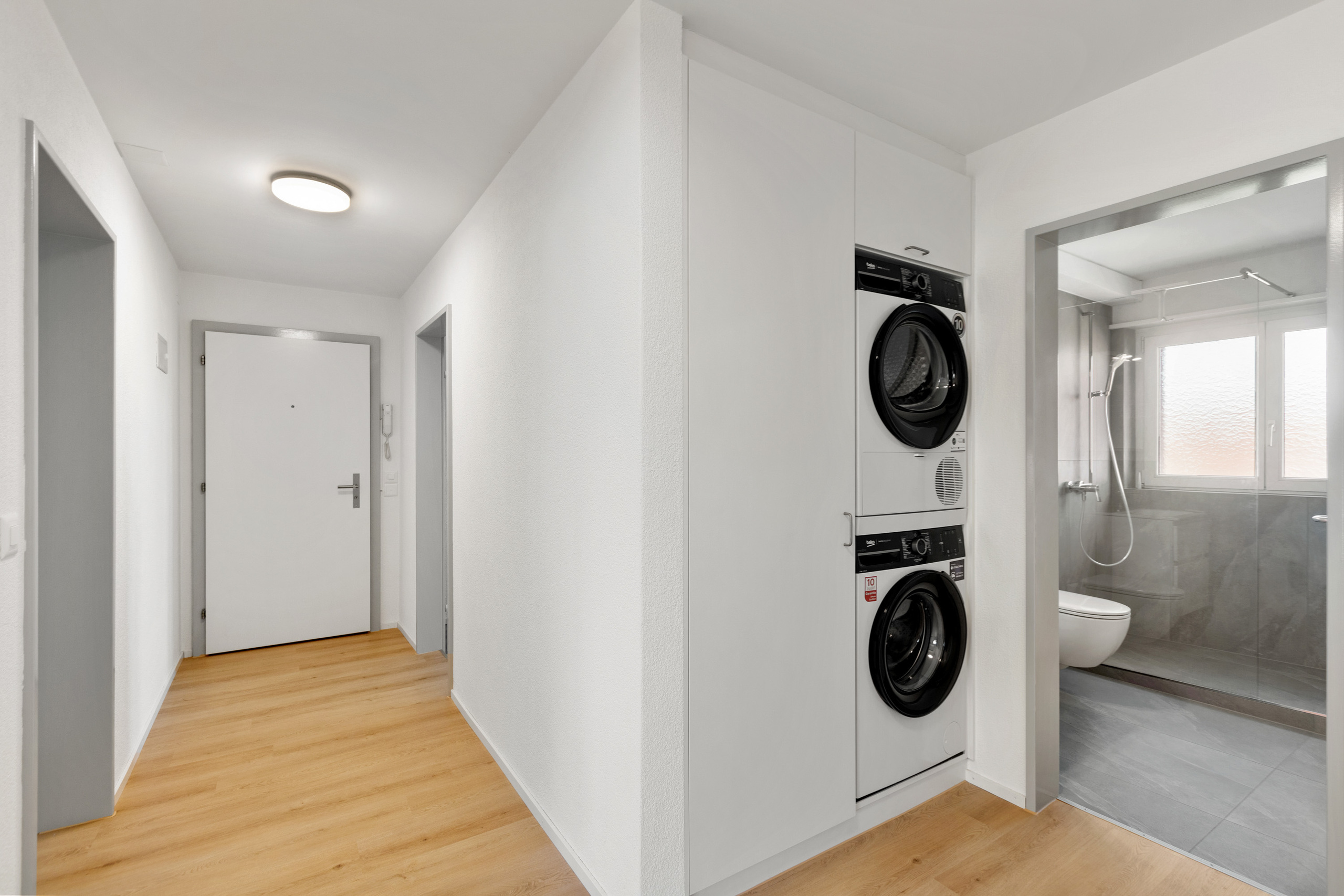 Heller und freundlicher Eingangsbereich mit praktischem Einbauschrank sowie integrierter Waschmaschine und Tumbler.