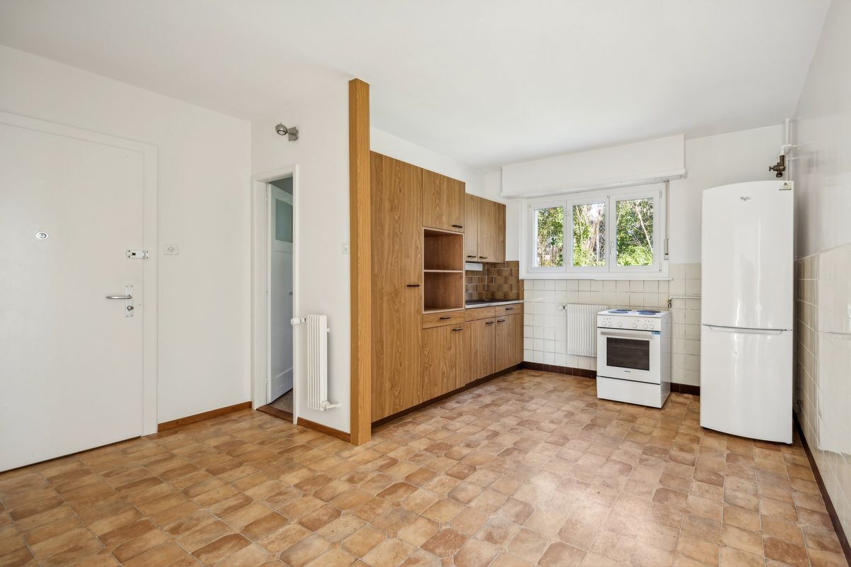 Cuisine équipée avec placards en bois et fenêtres lumineuses.